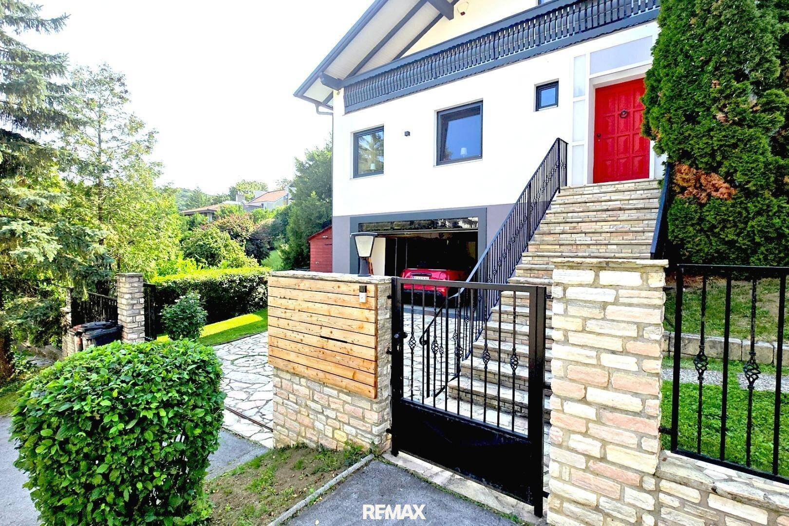 Seitenansicht des Hauses mit Zufahrt zur Garage und umzäuntem Gartenbereich.