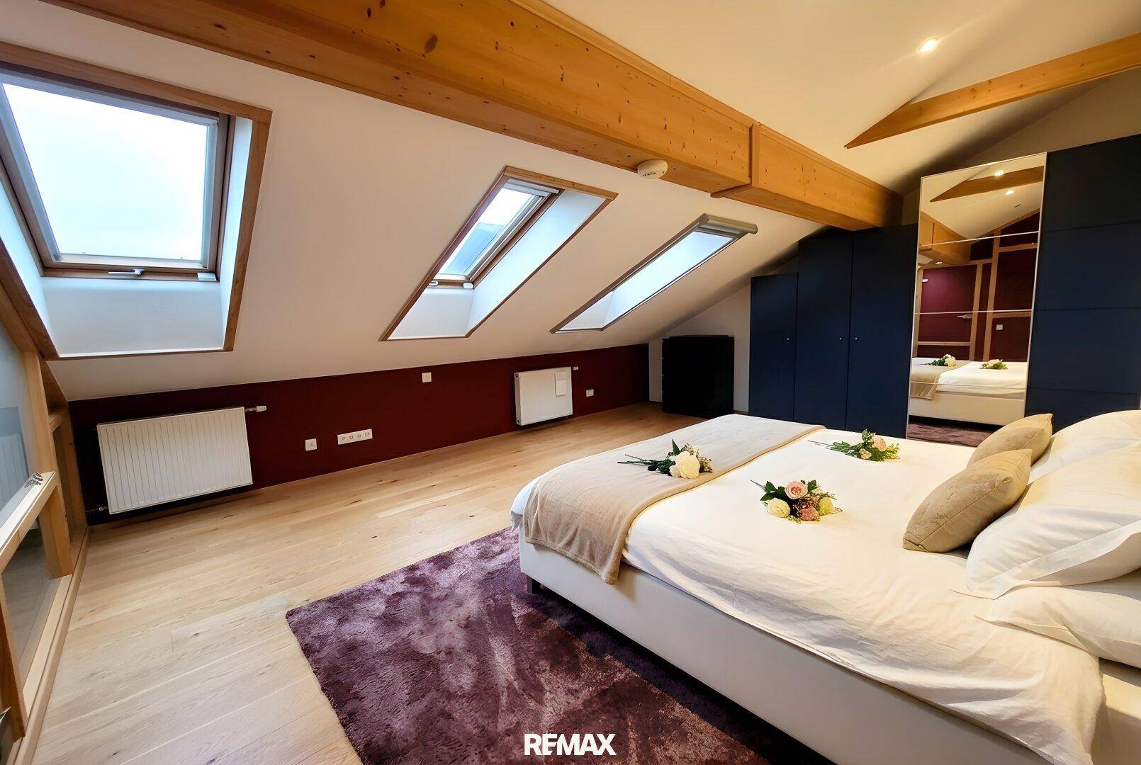 Gemütliches Schlafzimmer im Dachgeschoss mit Dachfenstern, Holzbalken und Einbauschränken.