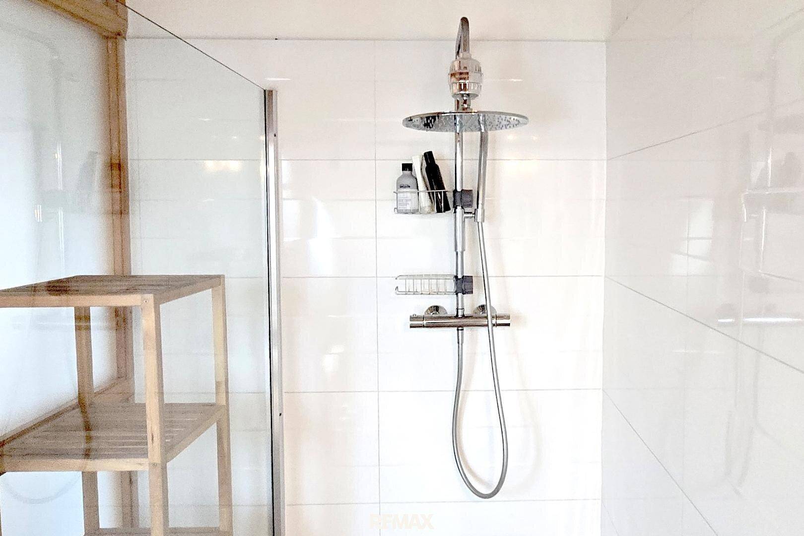 Moderne Duschkabine mit Regendusche und weißen Fliesen.