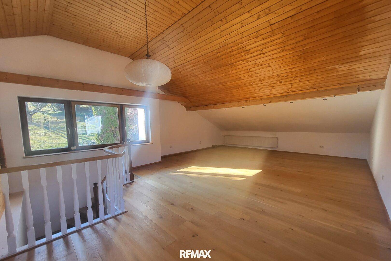 Geräumiger, unmöblierter Dachbodenraum mit Holzboden und viel Tageslicht.