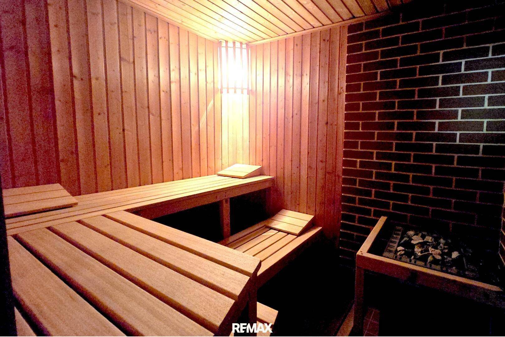 Traditionelle Holzsauna mit mehreren Bänken und einem Saunaofen für Entspannung.