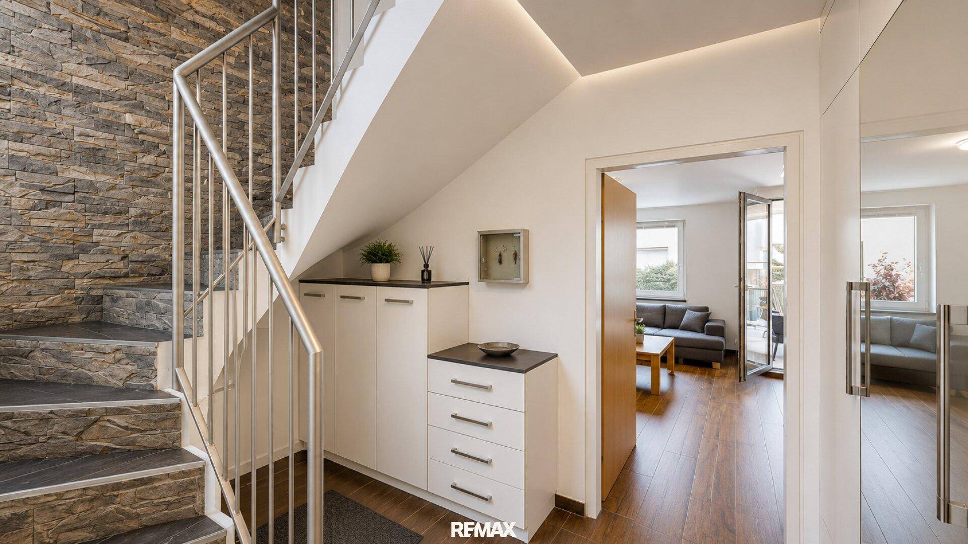 Moderner Eingangsbereich mit Steintreppe, Stauraum unter der Treppe und Zugang zum Wohnbereich.