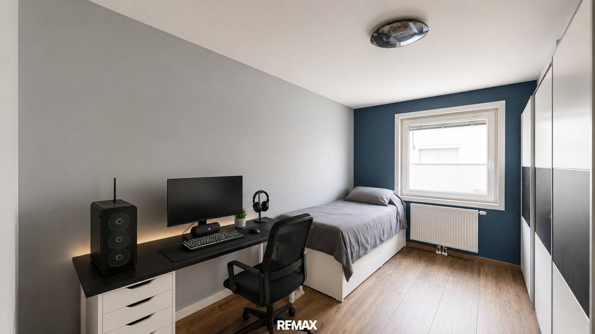 Jugendzimmer mit Einzelbett, Schreibtisch, Computer und Kleiderschrank, in Blautönen gehalten.