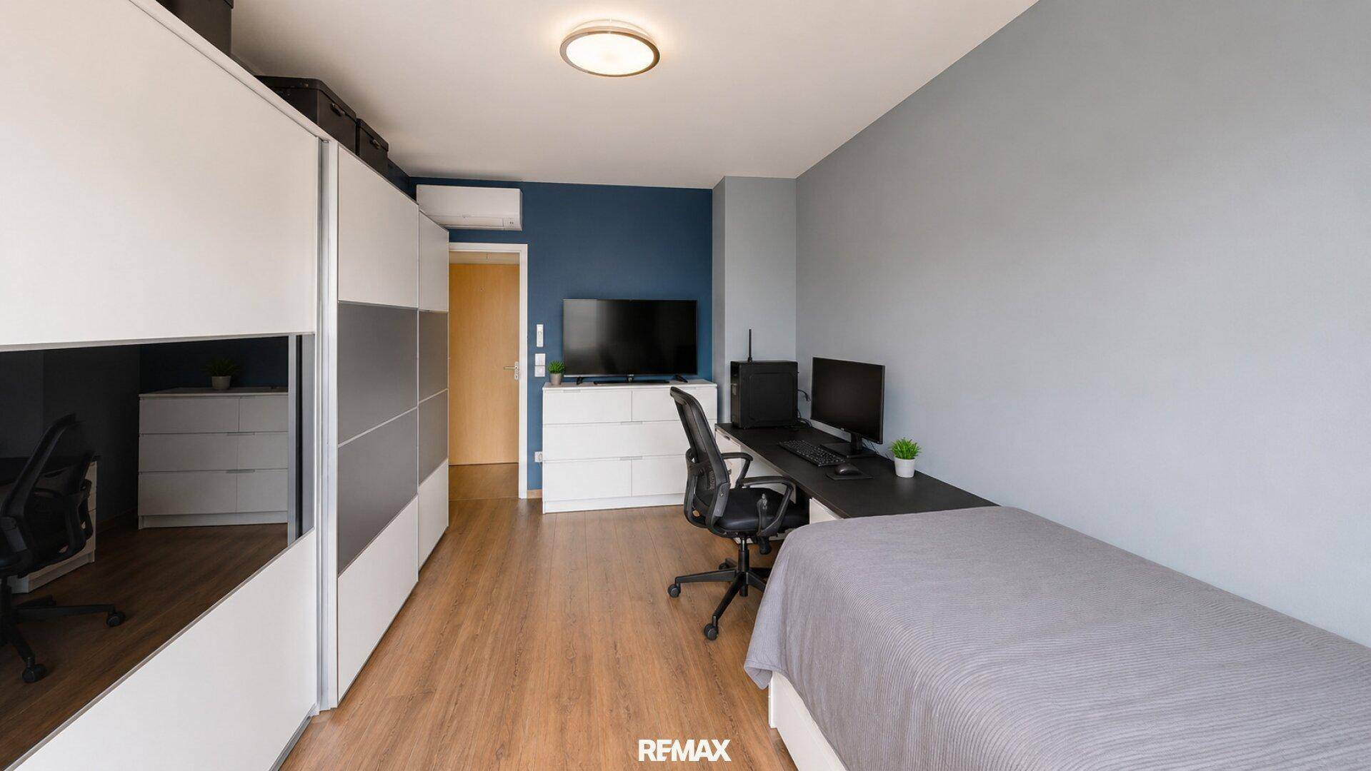 Geräumiges Schlafzimmer mit Einzelbett, Schreibtisch, Kleiderschrank und Blick auf den Innenhof.