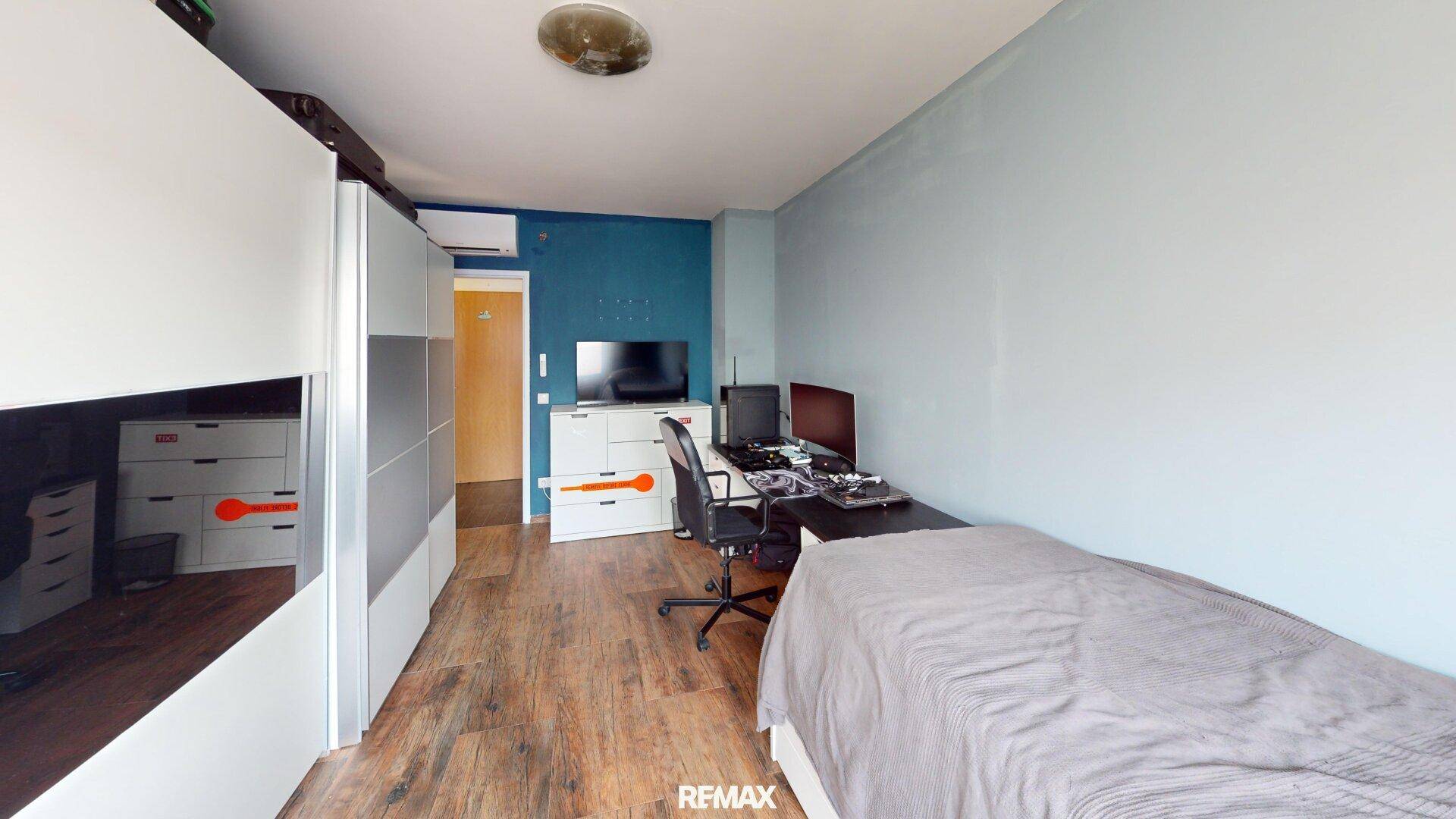 Helles Schlafzimmer mit Einzelbett, Schreibtisch und großem Kleiderschrank, in modernen Farben gestaltet.