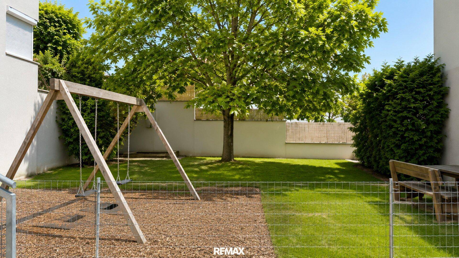 Gemeinschaftlicher Gartenbereich mit Schaukeln und viel Grün, ideal für Familien.