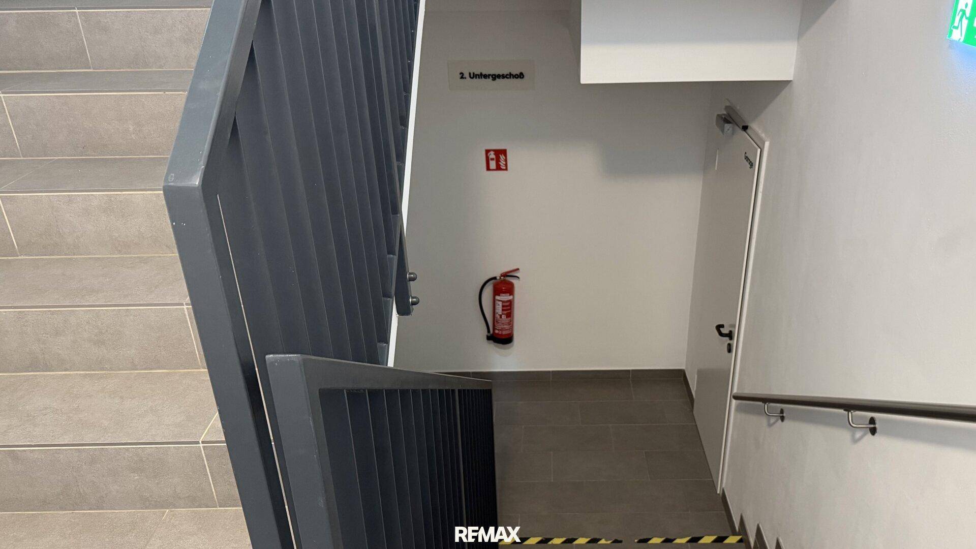 Modernes Treppenhaus mit robustem Geländer und Brandschutzvorrichtungen, führt ins Untergeschoss.
