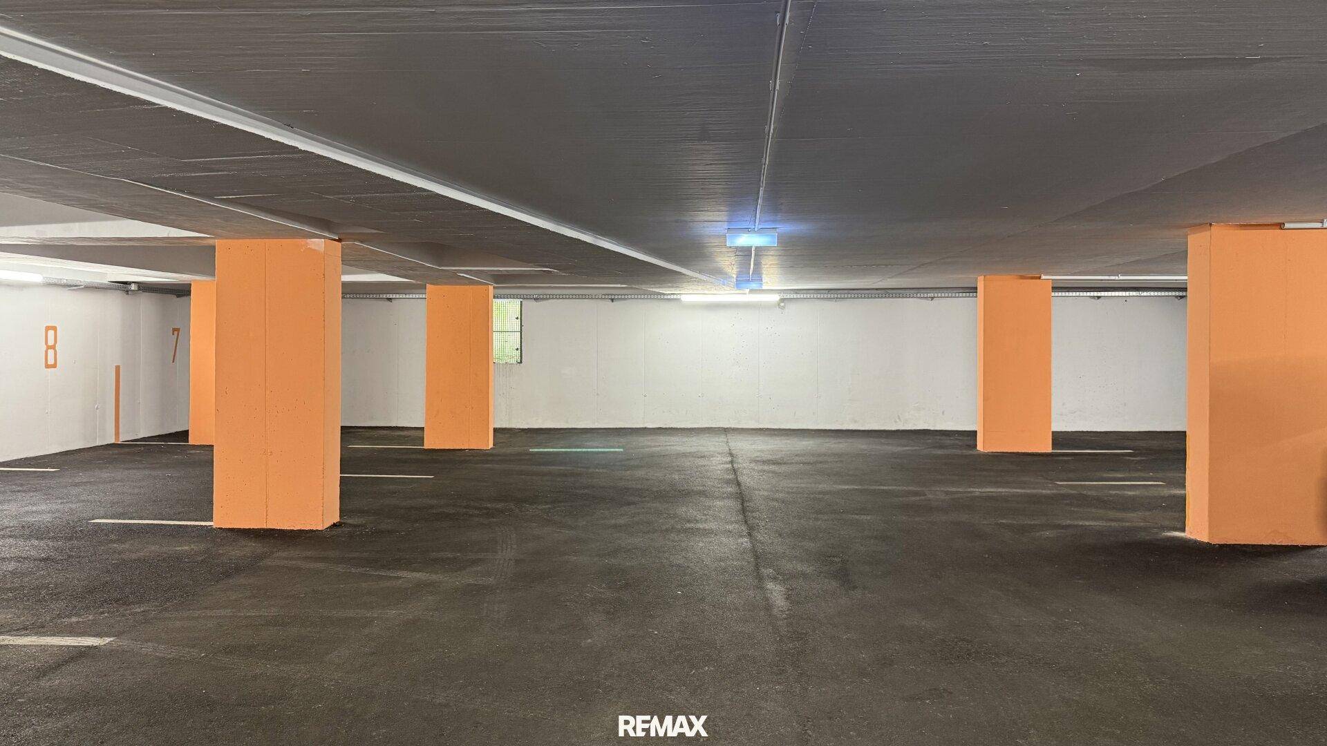 Geräumige Tiefgarage mit vielen Parkmöglichkeiten, gekennzeichneten Stellplätzen und Säulen.