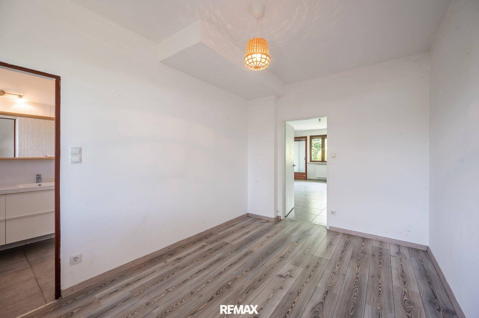 Leeres Zimmer mit modernem Laminatboden und hellem Licht.