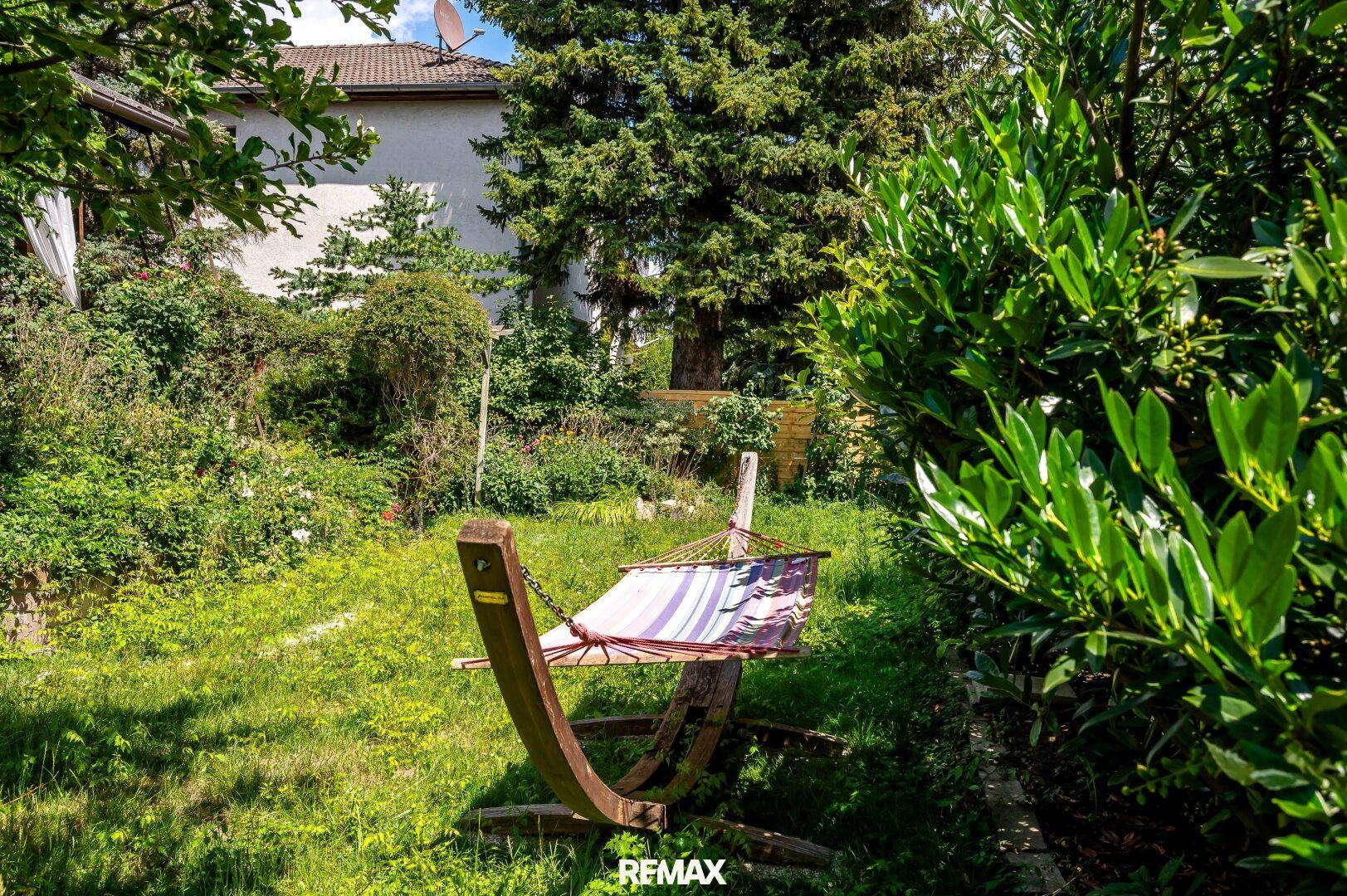 Entspannender Gartenbereich mit Hängematte und üppiger grüner Bepflanzung.