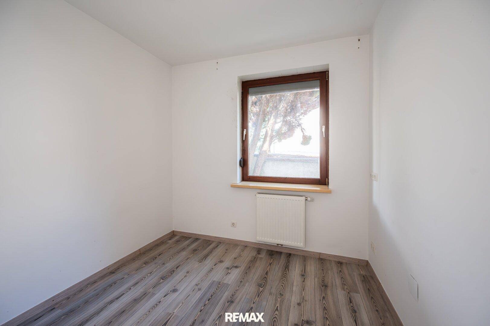 Helles Zimmer mit Laminatboden und Fenster, ideal als Schlaf- oder Arbeitszimmer.