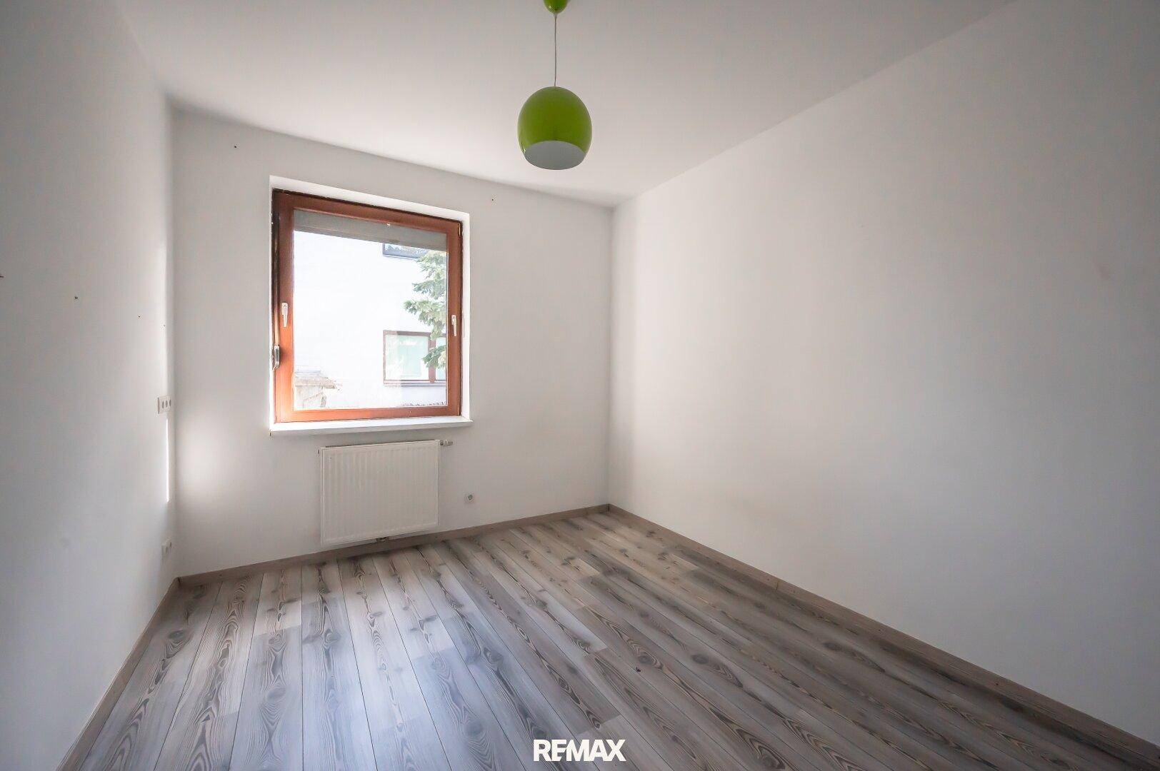 Helles Zimmer mit Laminatboden und Fenster, ideal als Schlaf- oder Kinderzimmer.