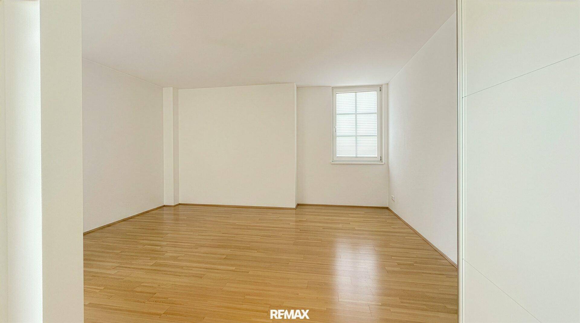 Ruhiges Zimmer mit Holzboden und einem Fenster, das für angenehmes Tageslicht sorgt.