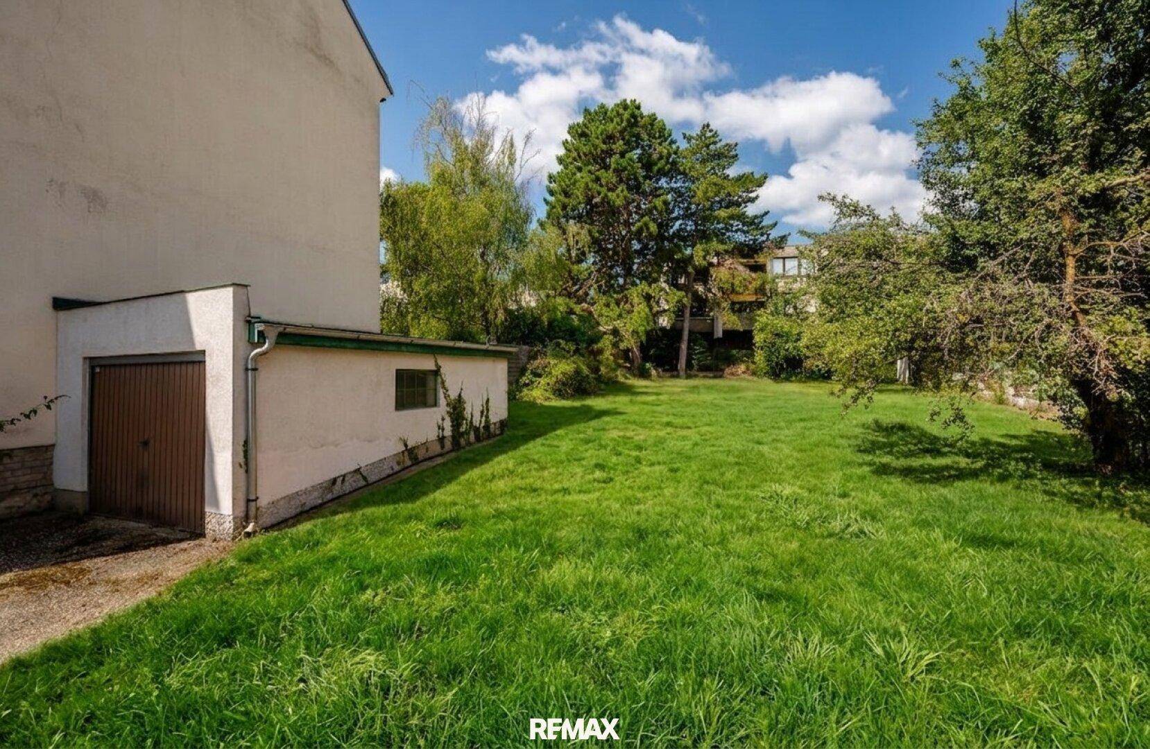 Seitlicher Blick auf eine Garage neben der weitläufigen Grünfläche des Grundstücks.
