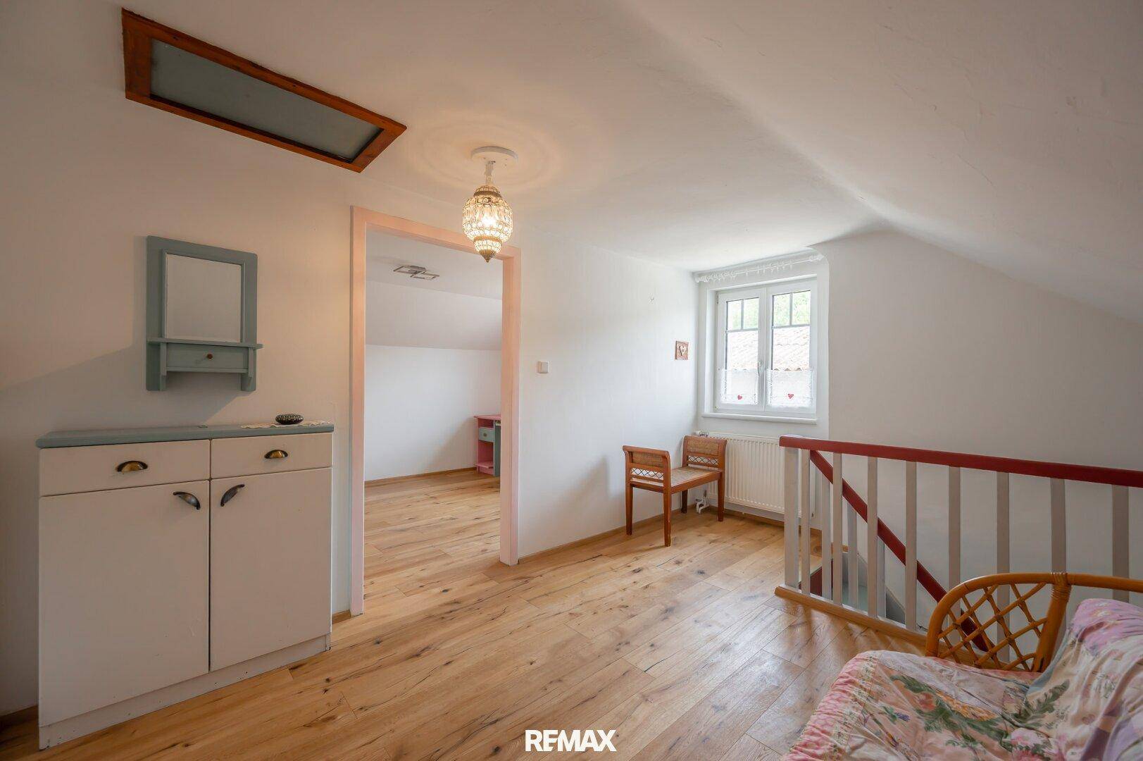 Dachgeschosszimmer mit Holzboden, Dachschräge und einem Fenster für natürliches Licht.