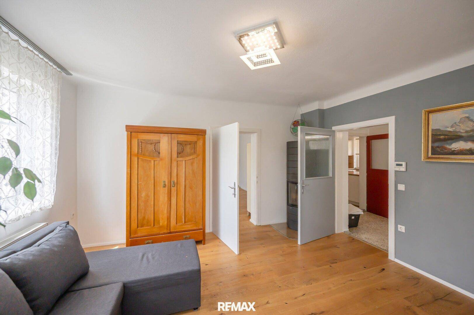 Wohnzimmer mit Holzboden und einem Kaminofen, der den Raum beheizt und Gemütlichkeit spendet.