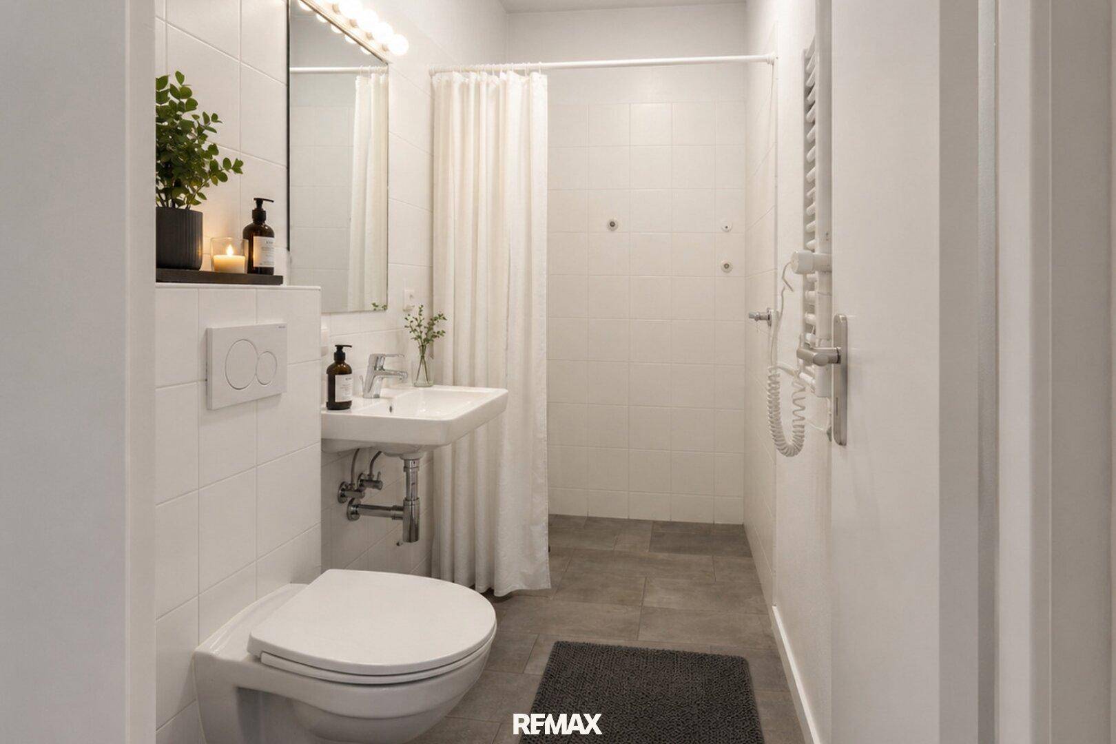 Helles Badezimmer mit weiß gefliesten Wänden, Toilette, Waschbecken und einer Duschkabine mit Vorhang.