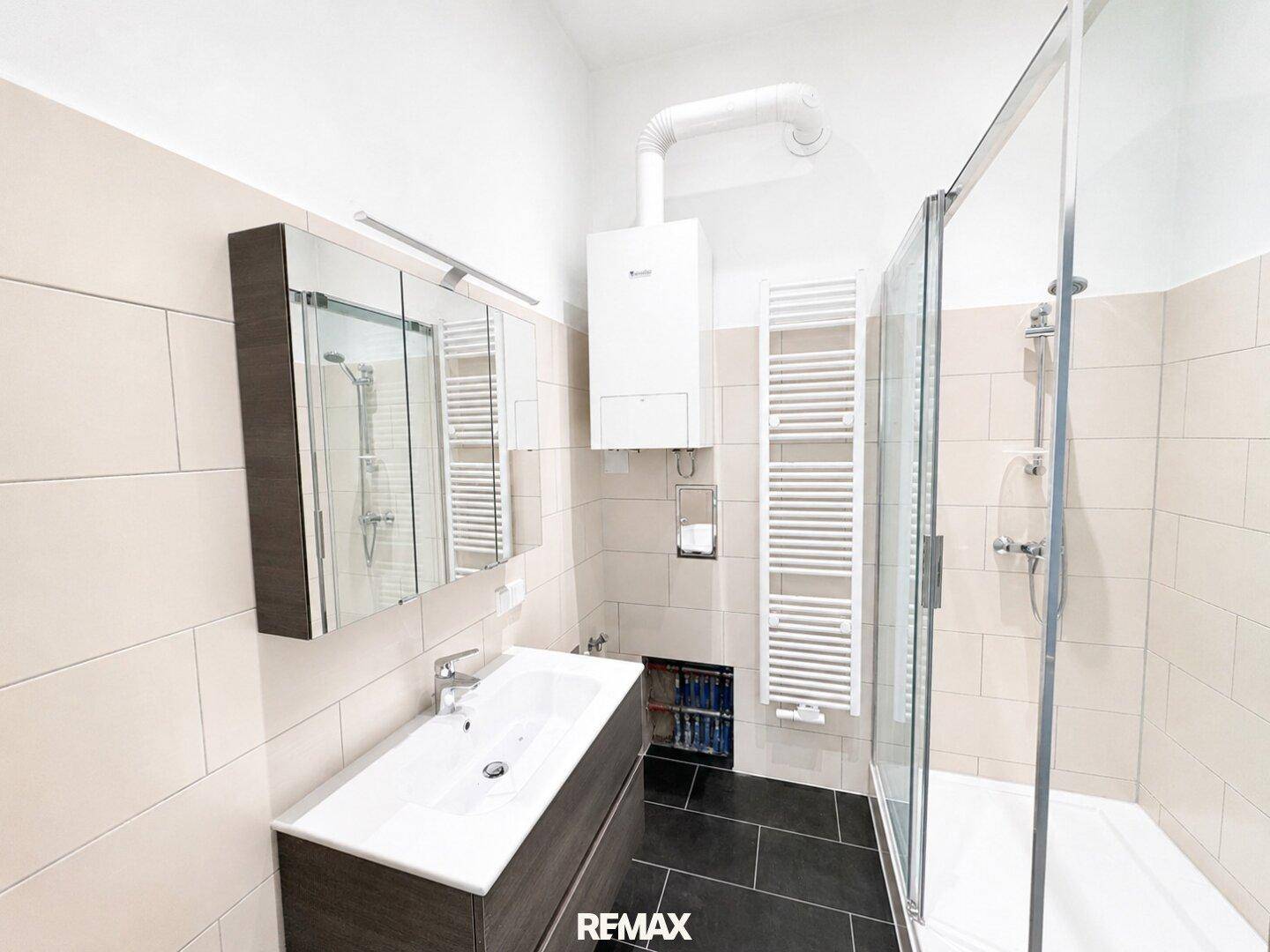 Modernes Badezimmer mit Duschkabine, Waschbecken und beheiztem Handtuchhalter.
