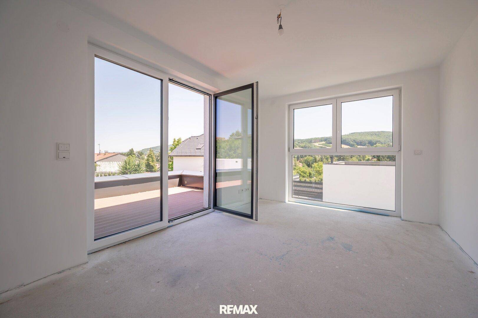 Heller Raum mit Zugang zu einer Terrasse und weitem Blick über die Landschaft.