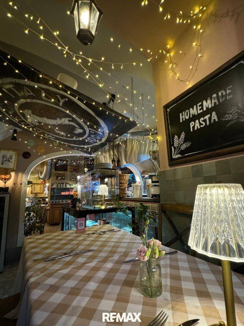 Nahaufnahme eines Tisches in einem Restaurant mit karierter Tischdecke, Lampe und einer Tafel mit Speiseangebot.