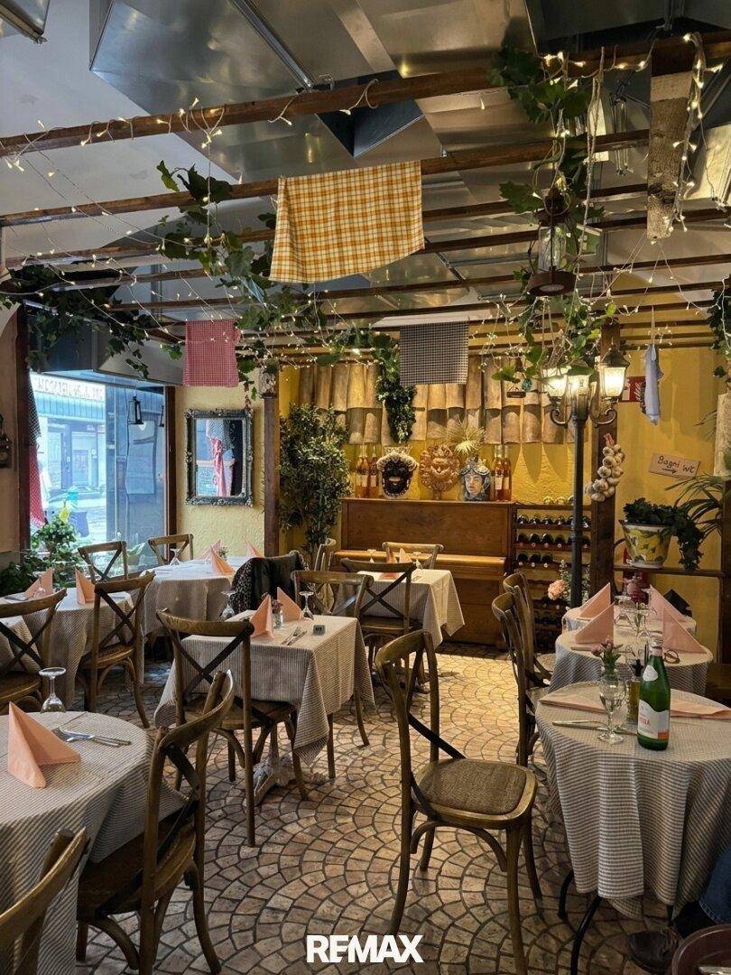 Gemütlicher Restaurant-Speisesaal mit vielen Tischen, Stühlen, Lichterketten und rustikaler Dekoration.