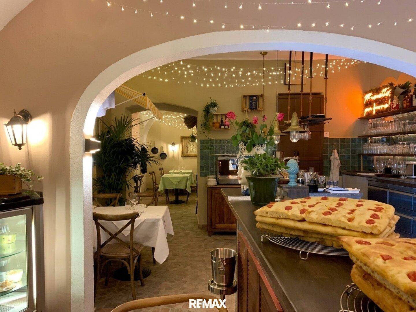 Rustikales Restaurant-Interieur mit warmem Licht, Holztischen und einer Theke mit frischem Gebäck.