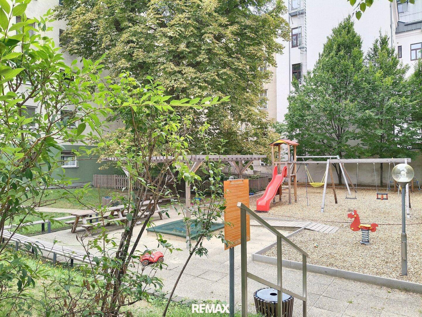Kinderspielplatz mit Rutsche und Schaukeln im grünen Innenhof der Wohnanlage.