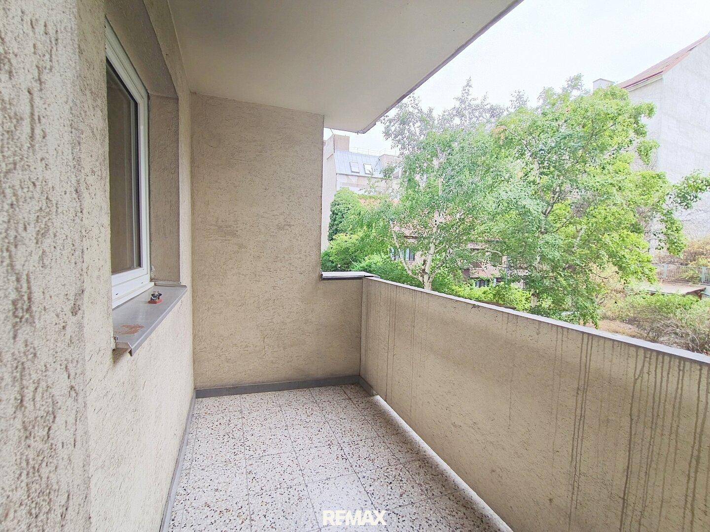 Kleiner Balkon mit Fliesenboden und Blick ins Grüne, ideal für entspannte Stunden im Freien.