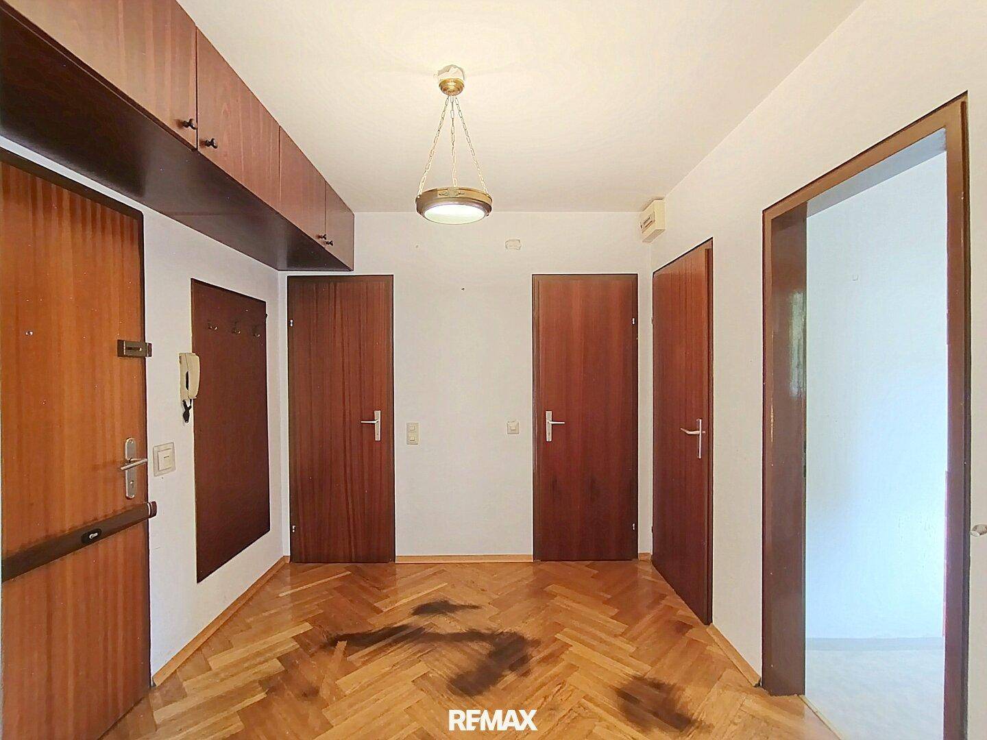 Eingangsbereich mit Holzparkett und mehreren Türen, die zu den verschiedenen Räumen führen.