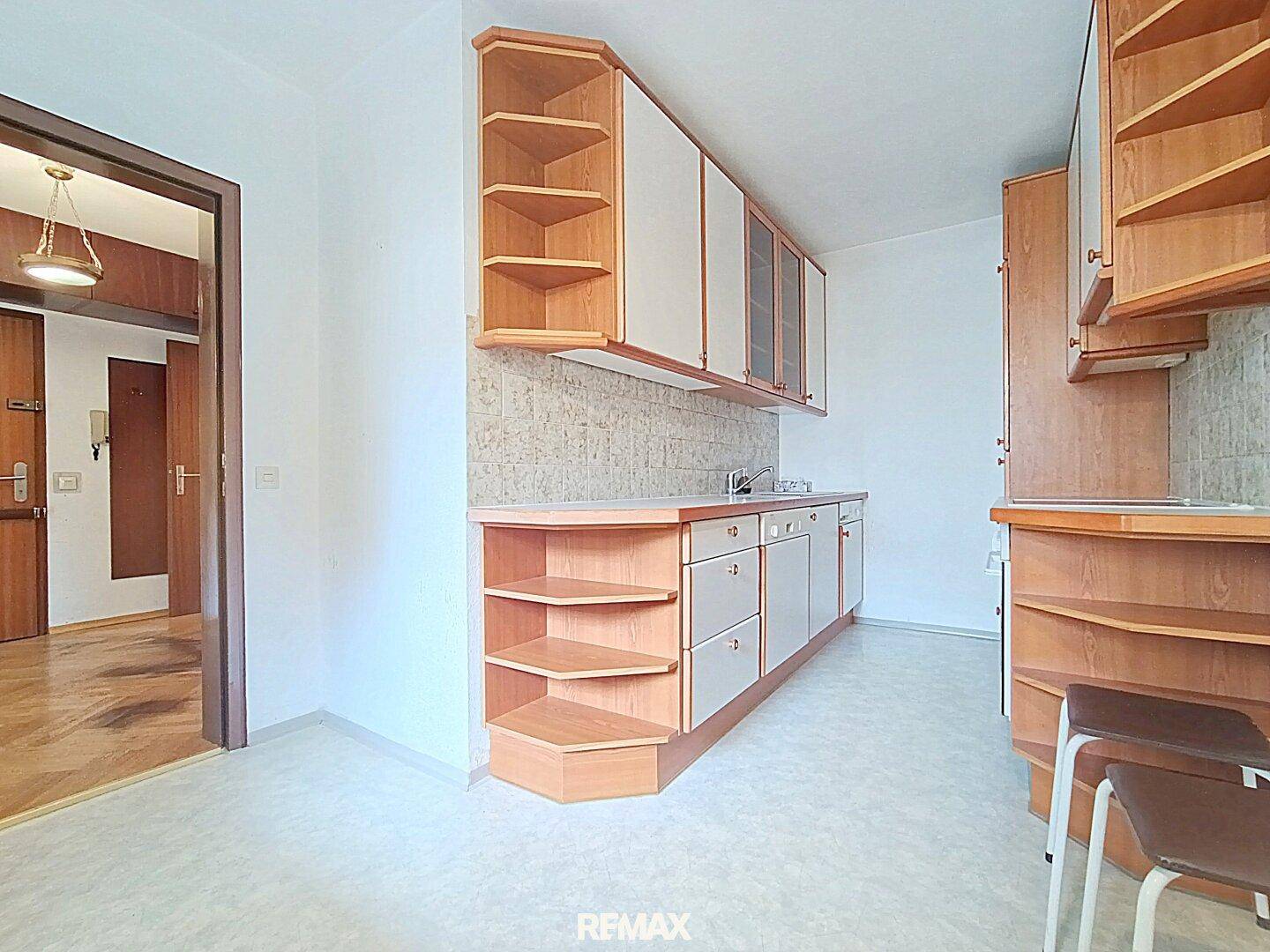 Funktionale Küche mit Holzschränken und integrierter Spüle, bereit für eine Modernisierung.