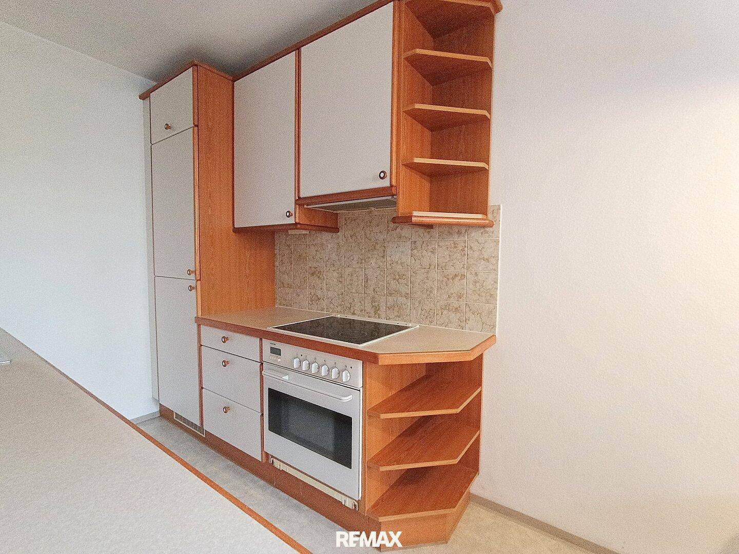 Küchenbereich mit Herd, Backofen und praktischen Regalen für zusätzlichen Stauraum.
