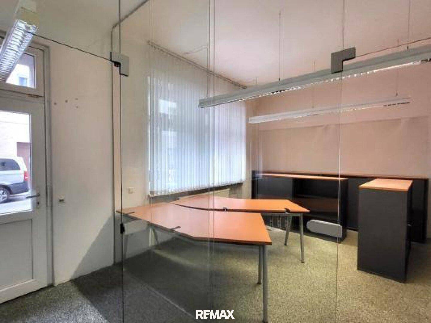 Büroraum mit Glasabtrennung, Schreibtischen und Blick durch das Fenster.
