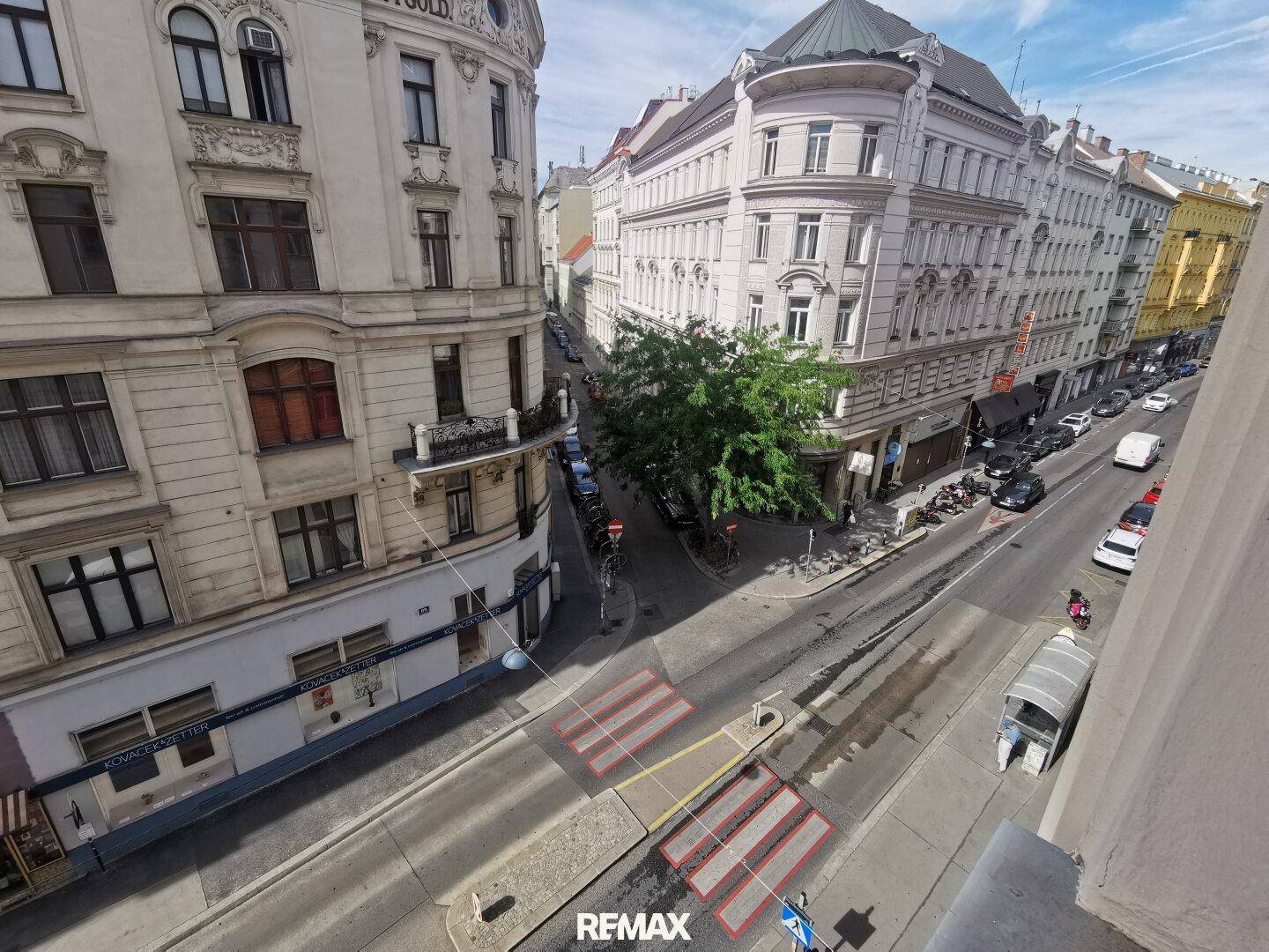 Blick von oben auf eine belebte Stadtstraße mit historischen Gebäuden und Fußgängerüberweg.