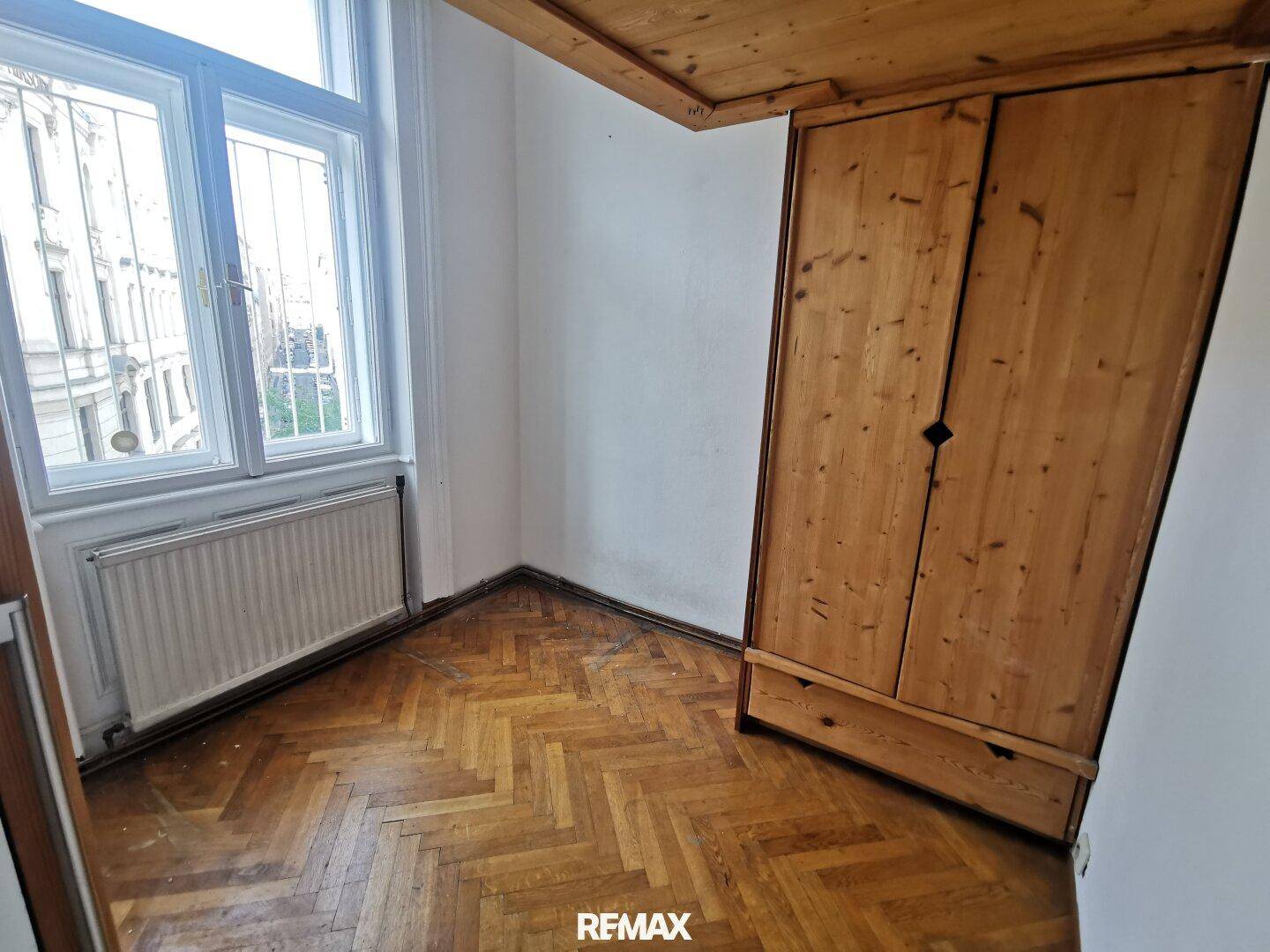 Kleines Zimmer mit Fischgrätparkett und Einbauschrank aus Holz, bietet praktischen Stauraum.