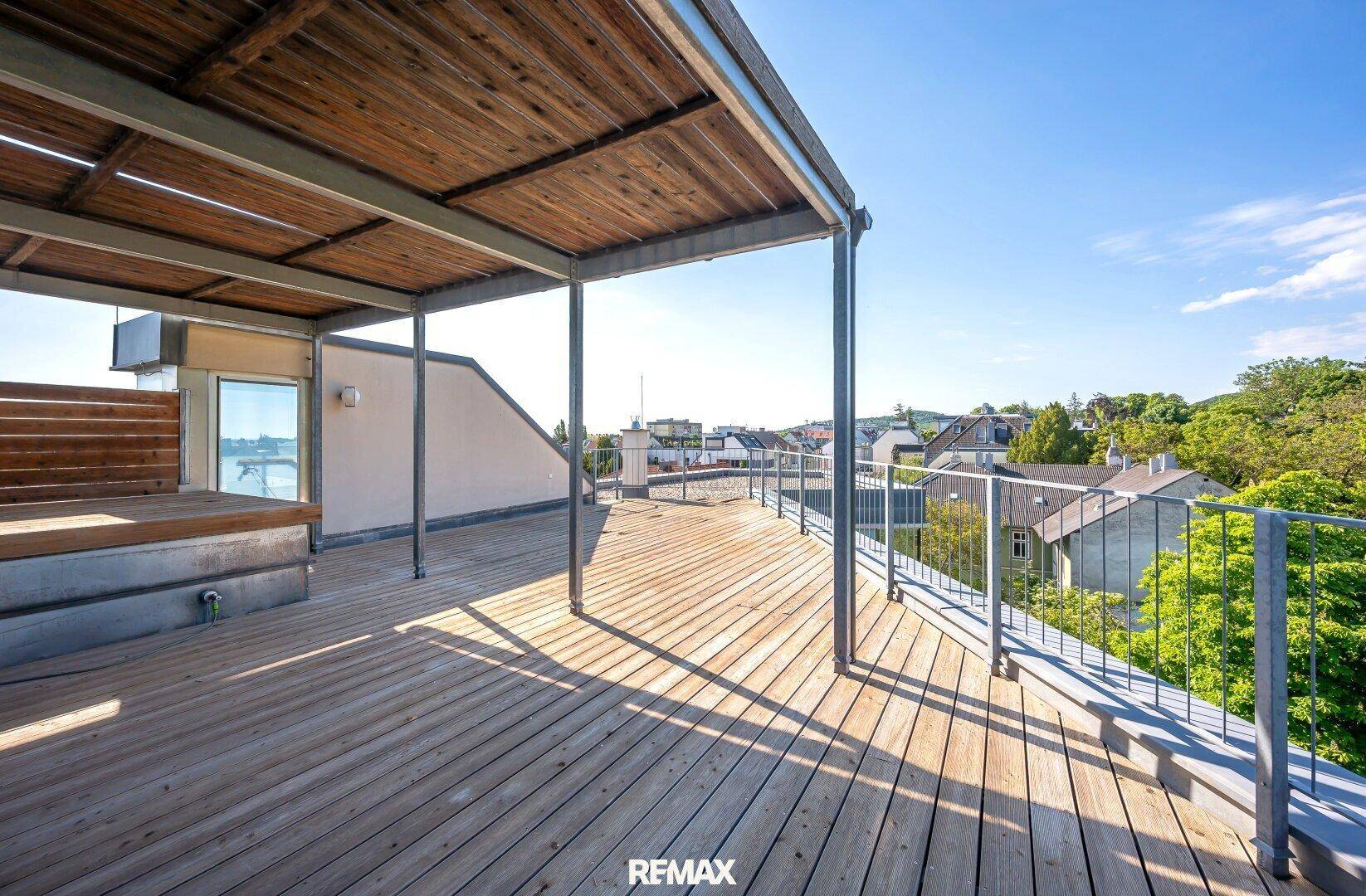 Geräumige Dachterrasse mit Holzbelag, Überdachung und weitem Blick über die Stadt.
