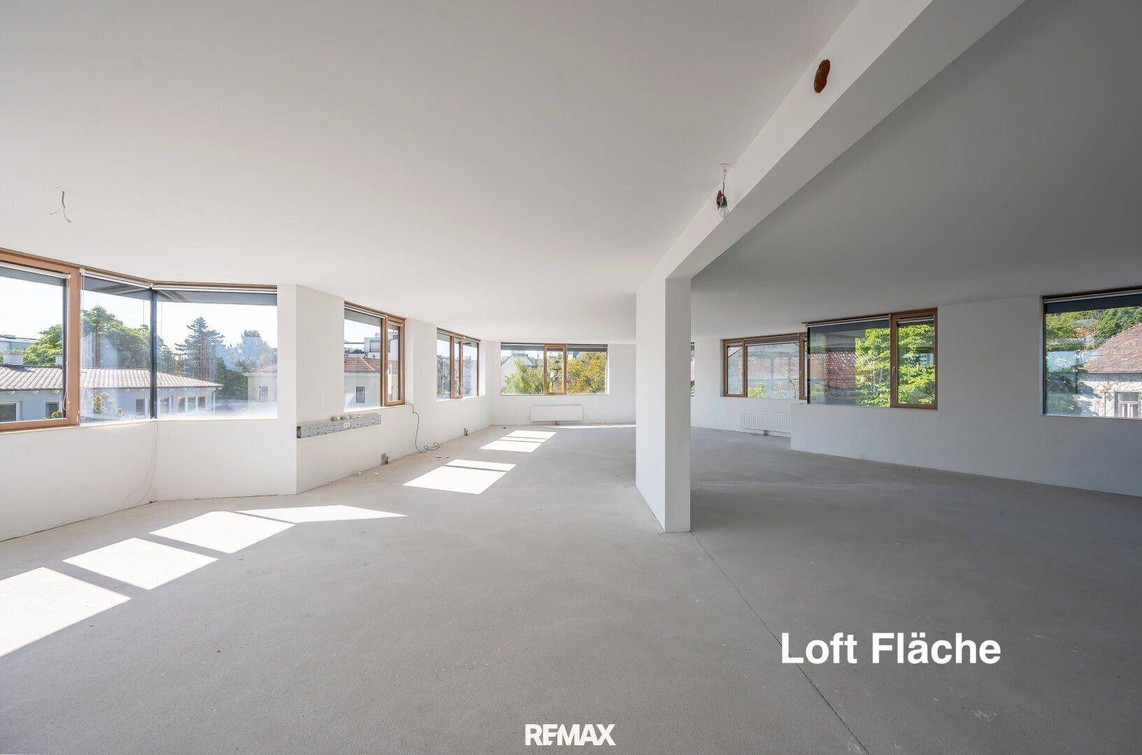 Großer, heller Loftbereich mit vielen Fenstern und Betonboden, bereit zum Ausbau.