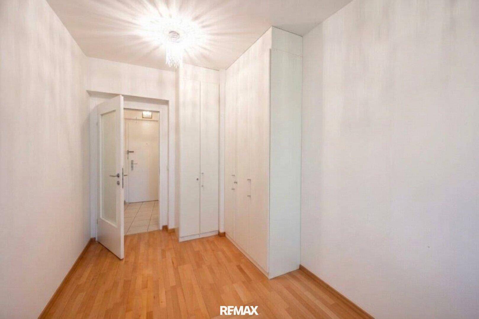 Kleines Schlafzimmer mit Parkettboden und praktischen Einbauschränken für Stauraum.
