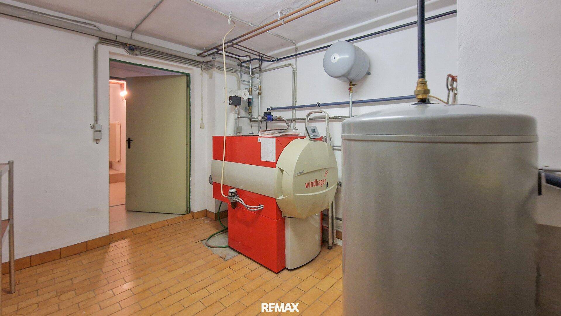 Heizungsraum im Keller mit einem großen Heizkessel und Warmwasserspeicher.