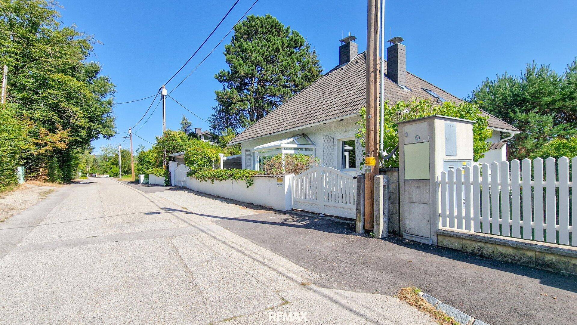 Ansicht des Hauses von der Straße mit weißem Zaun und gepflegtem Vorgarten.