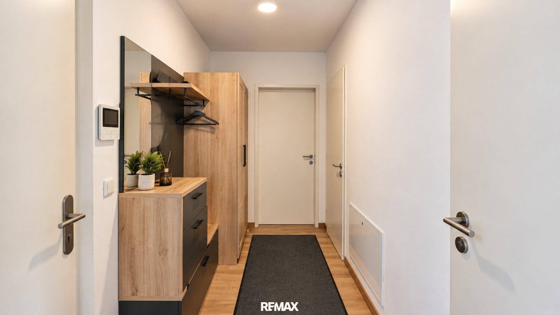 Heller Eingangsbereich mit Garderobe, Holzboden und weiß gestrichenen Wänden.