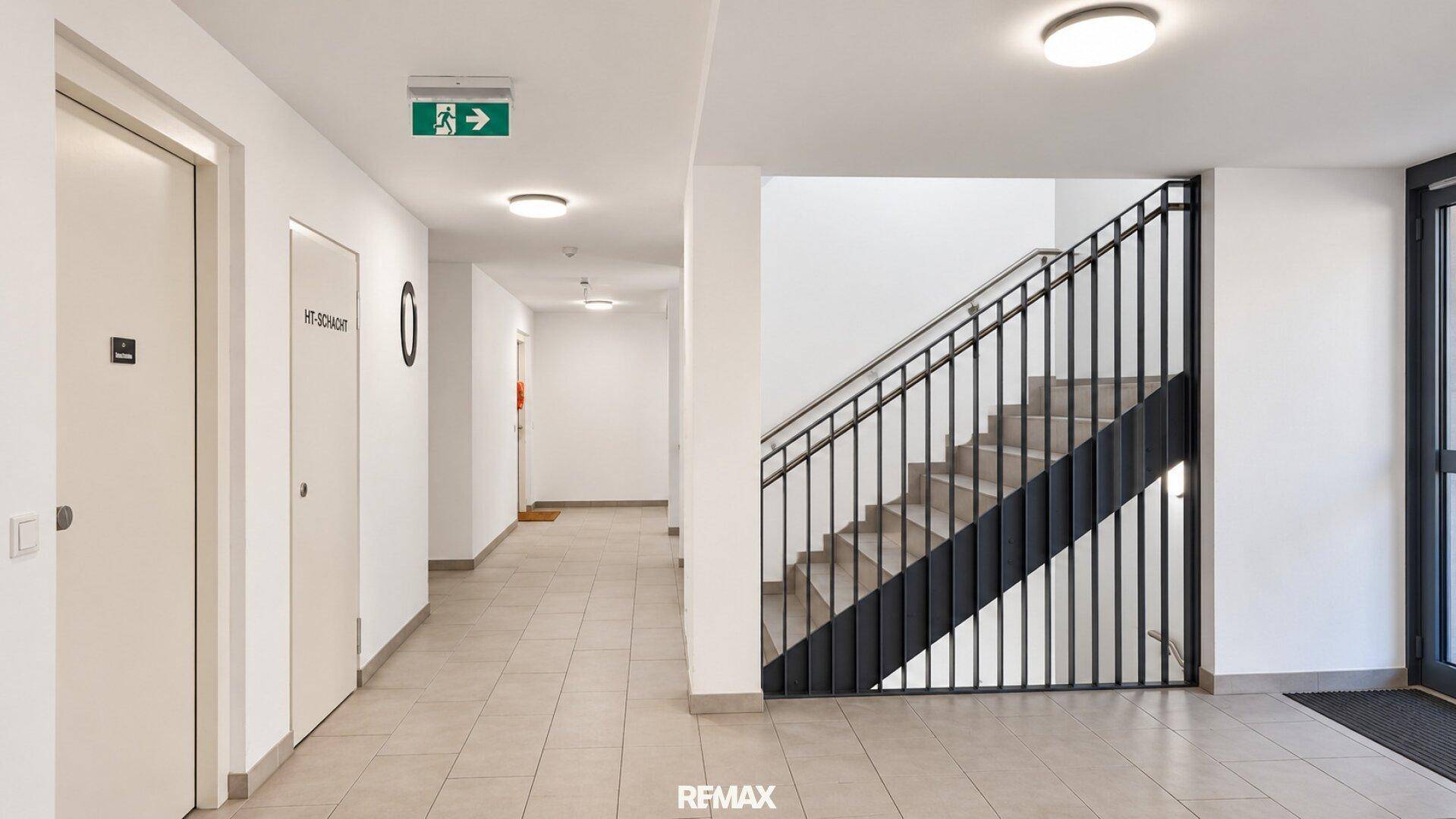 Heller Flur im Mehrfamilienhaus mit Treppenhaus und Zugang zu den Wohneinheiten.