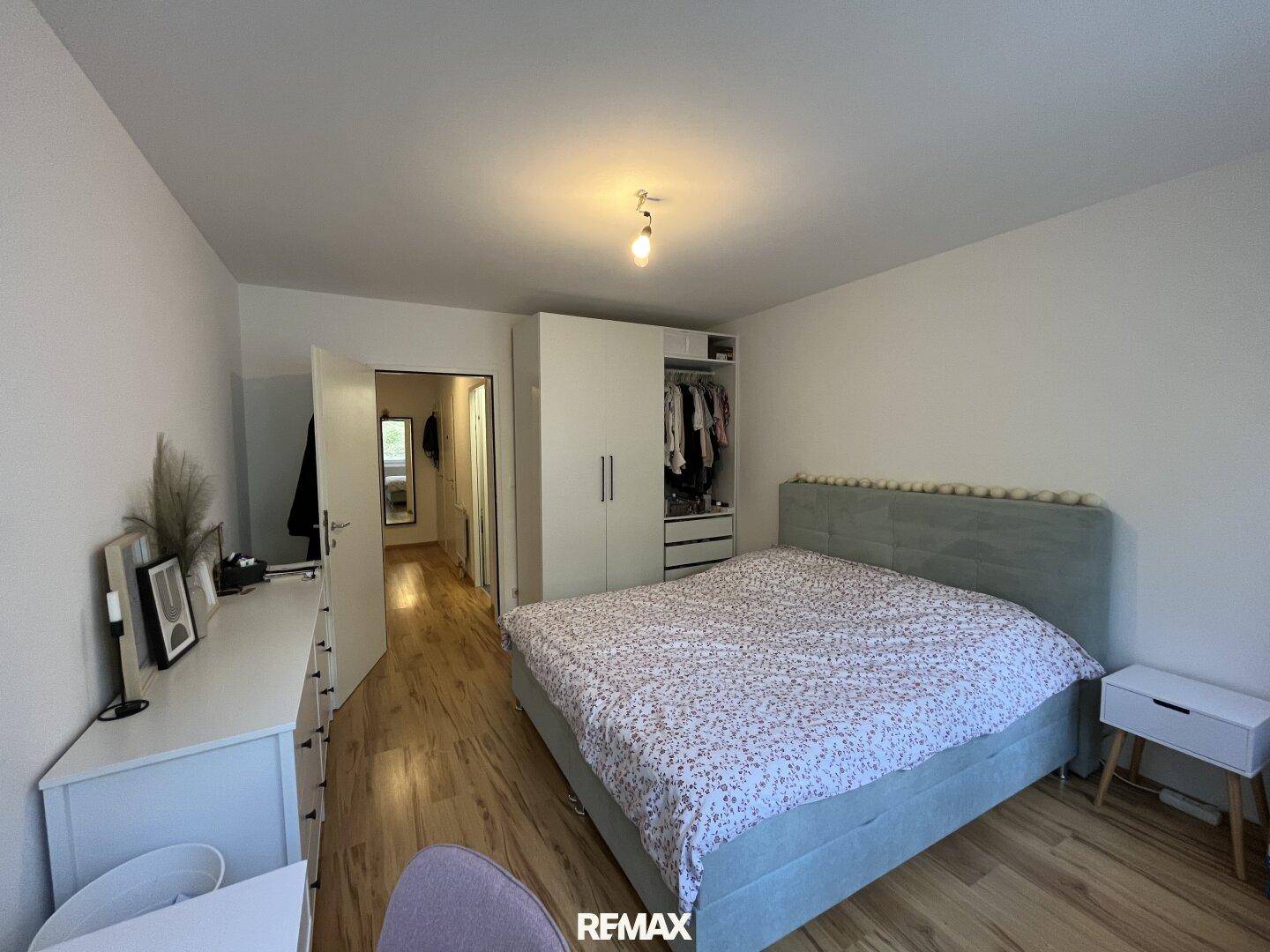 Gemütliches Schlafzimmer mit Holzboden, großem Bett und integriertem Kleiderschrank.