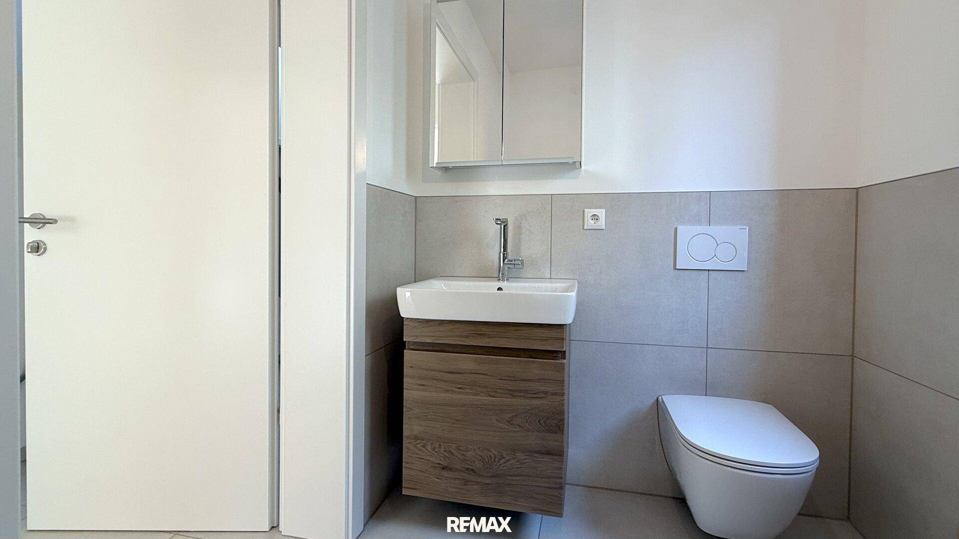 Modernes Gäste-WC mit wandhängendem WC, Einzelwaschbecken und Spiegelschrank.