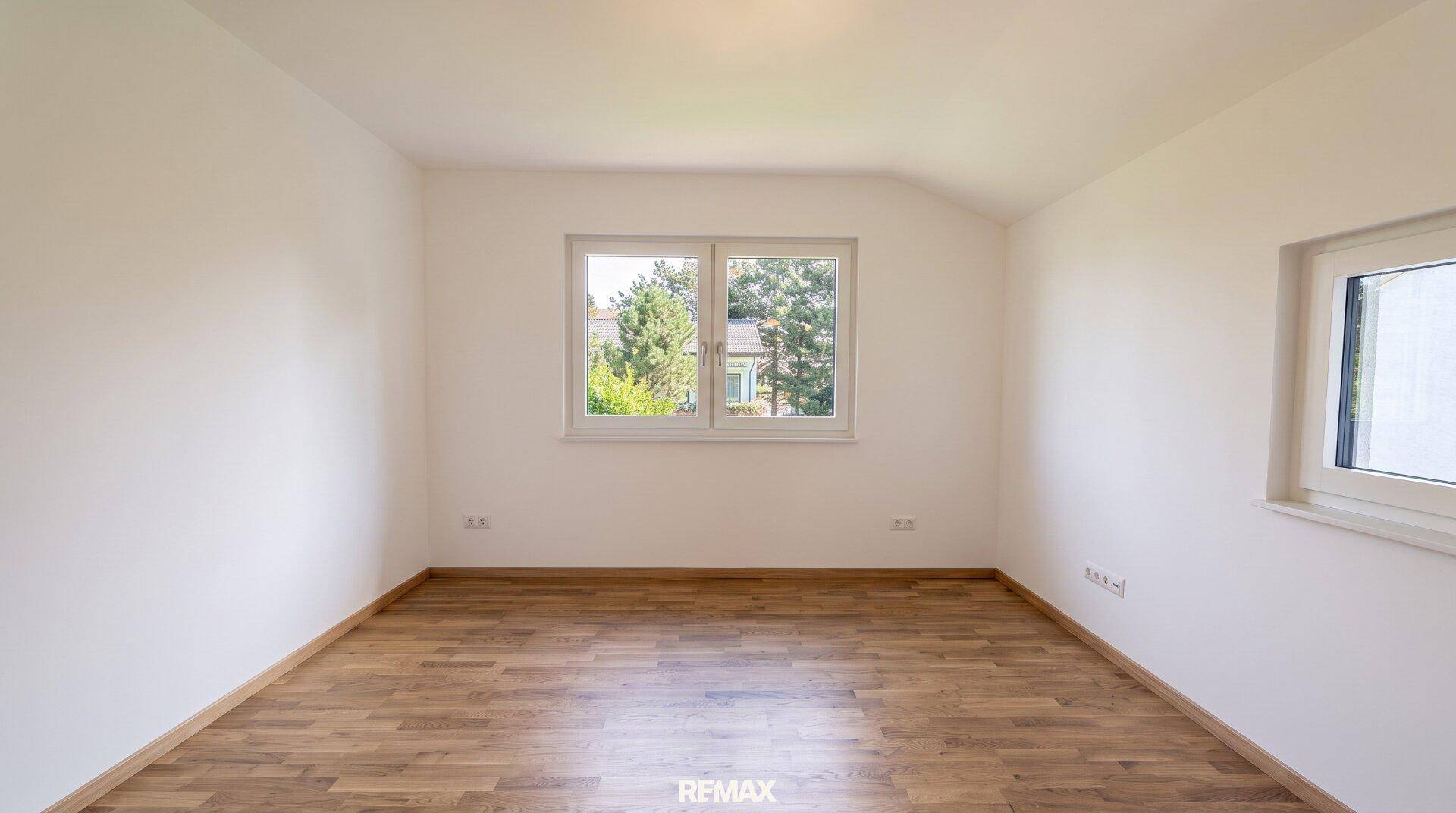 Geräumiges, unmöbliertes Zimmer mit Holzboden und großen Fenstern, bereit zur individuellen Gestaltung.