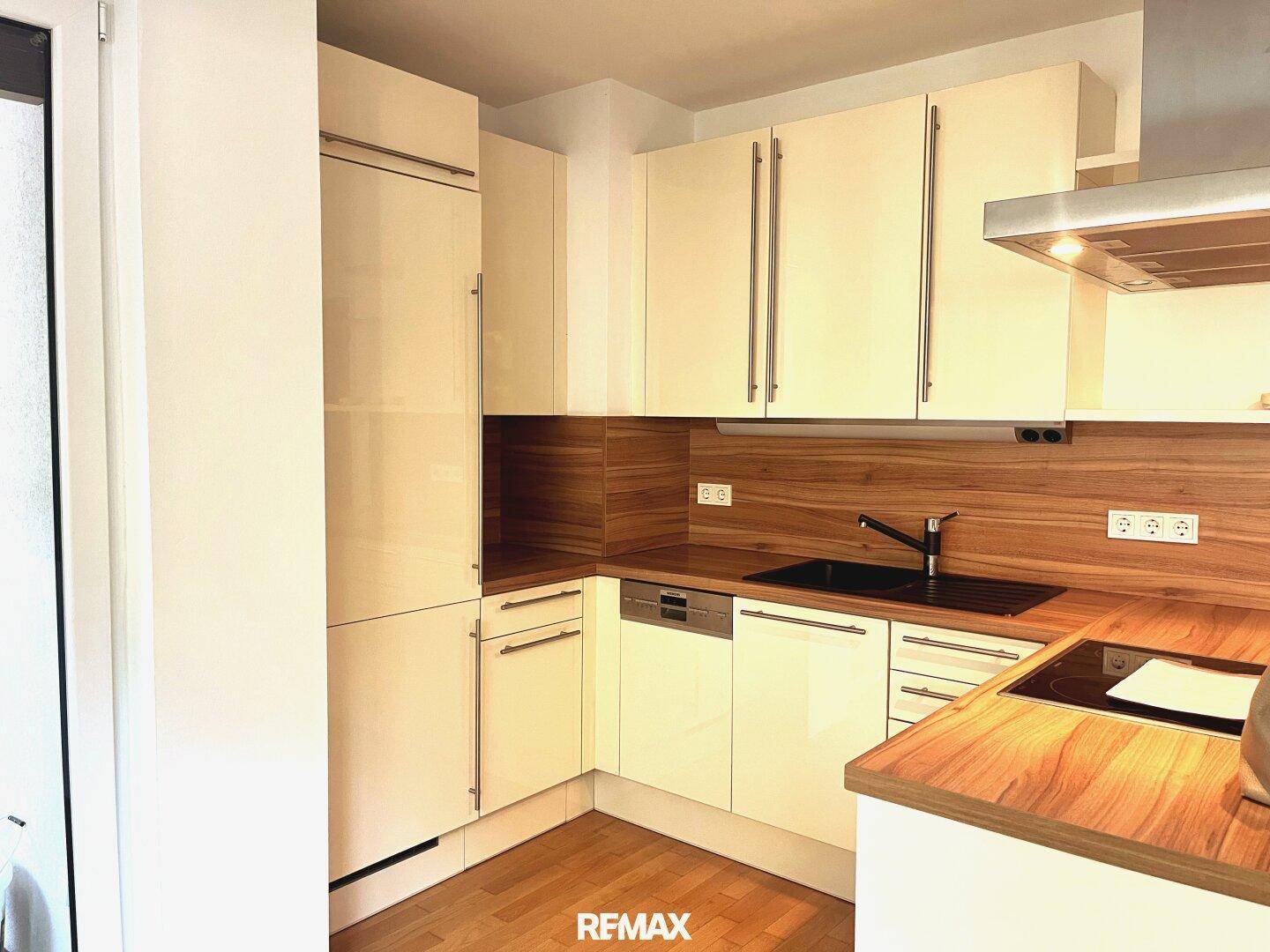 Detailansicht der modernen Küche mit glänzenden Fronten, Spülmaschine und Holz-Akzenten.