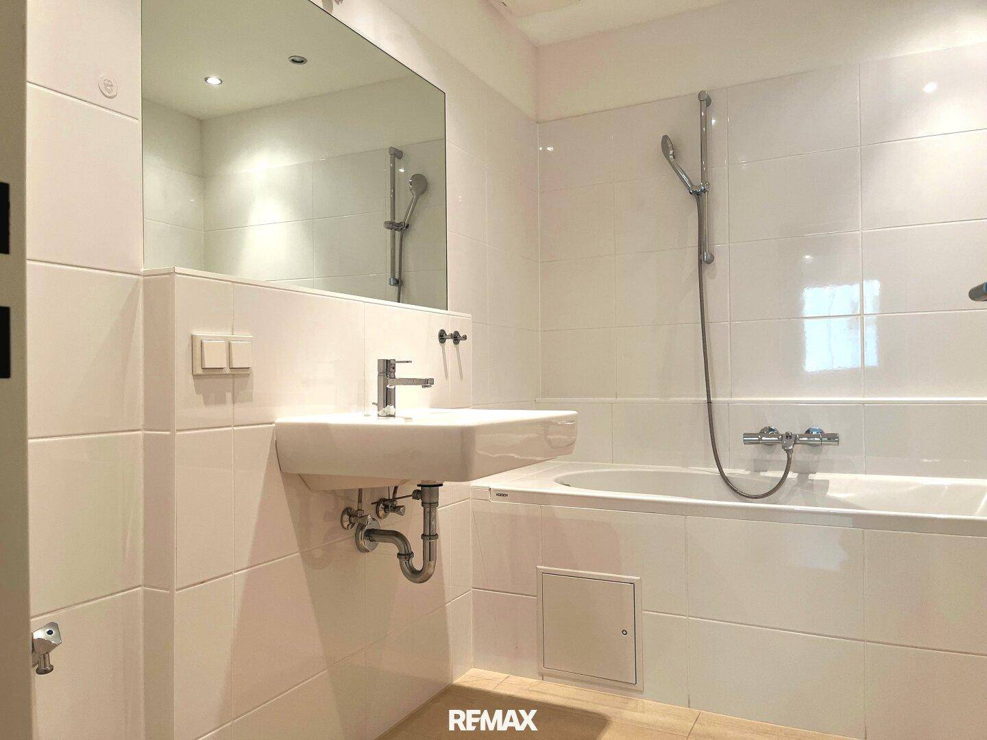 Modernes Badezimmer mit Badewanne, Waschbecken und großem Spiegel.