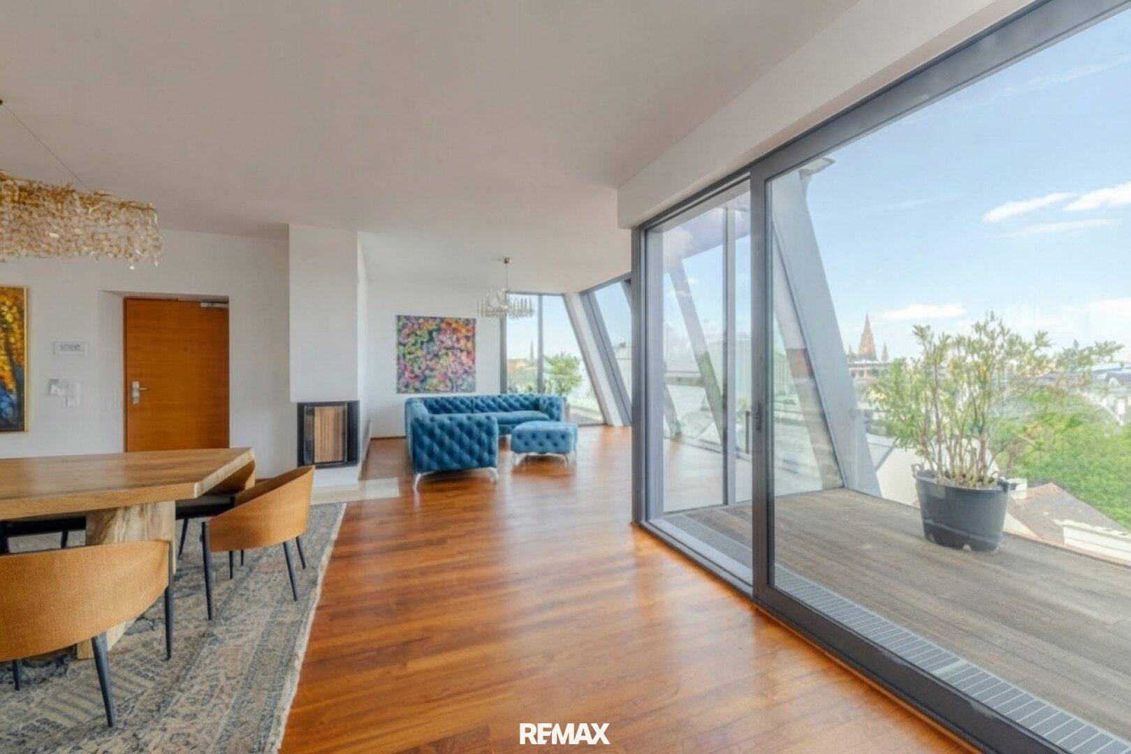 Offener Wohn- und Essbereich mit Holzboden, großen Glasfronten und Zugang zur Terrasse.