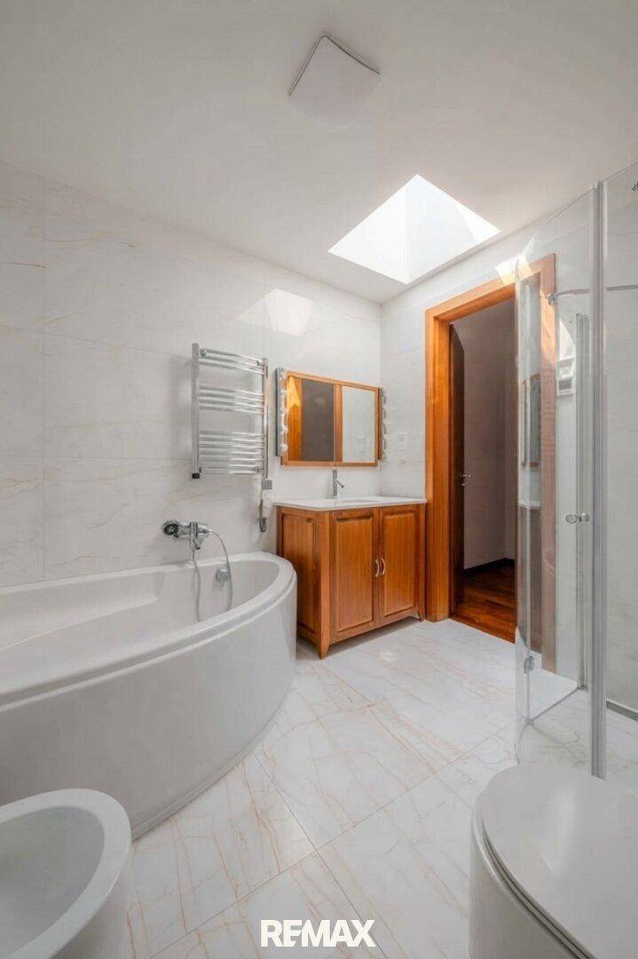 Modernes Badezimmer mit Badewanne, Dusche, Bidet und Dachfenster für natürliches Licht.