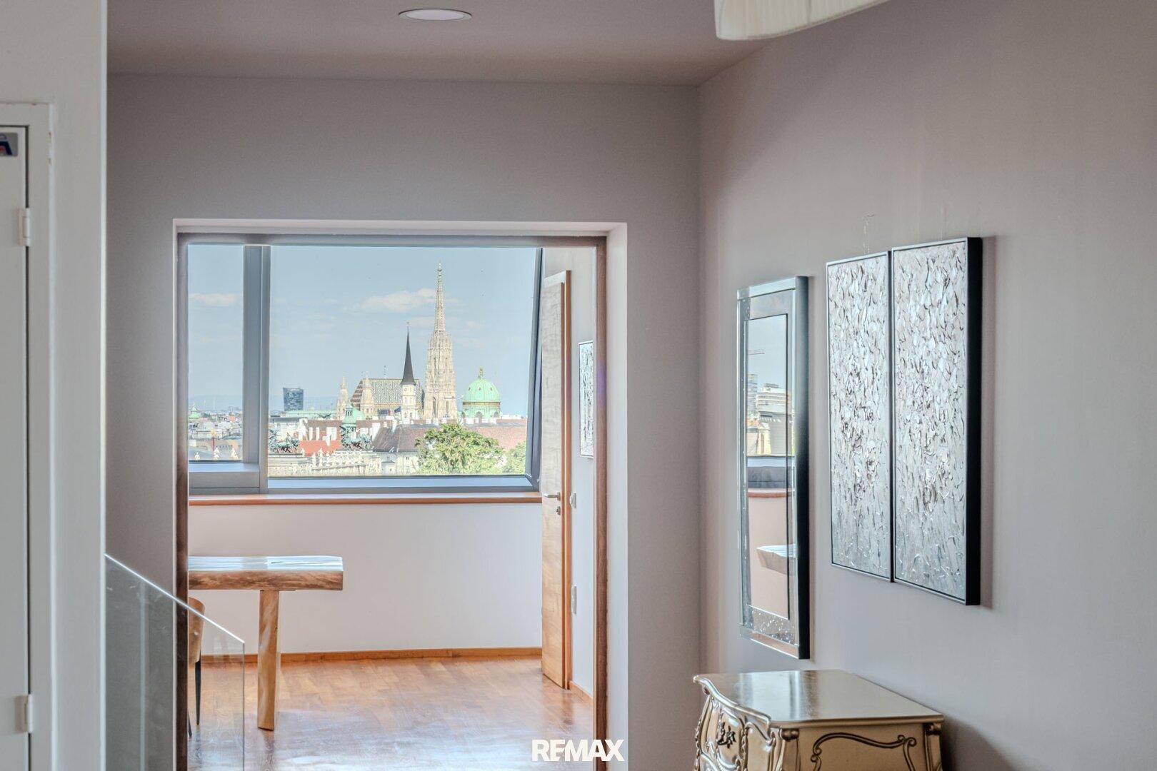 Heller Flur mit Holzboden und weitem Blick auf die Stadt durch eine große Türöffnung.