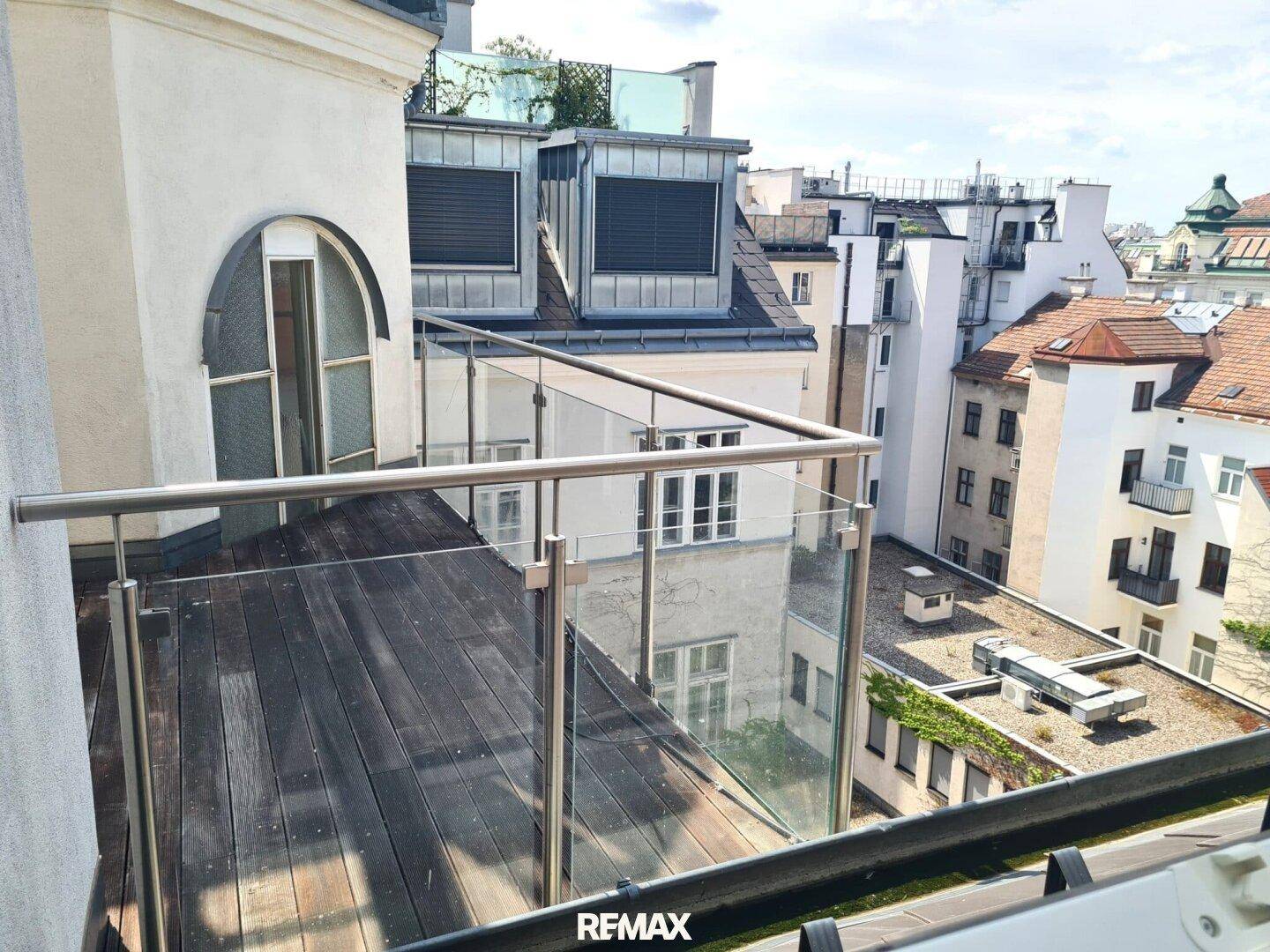 Geräumiger Balkon mit Holzboden und Glasgeländer bietet einen Blick über die Stadt.